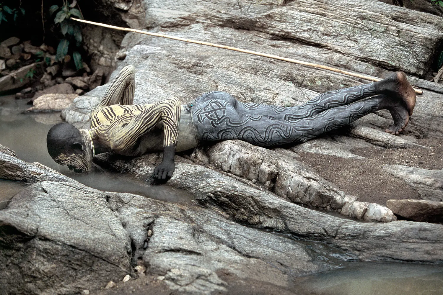 Photographie d'un guerrier de la vallée de l'Omo buvant dans un ruisseau.